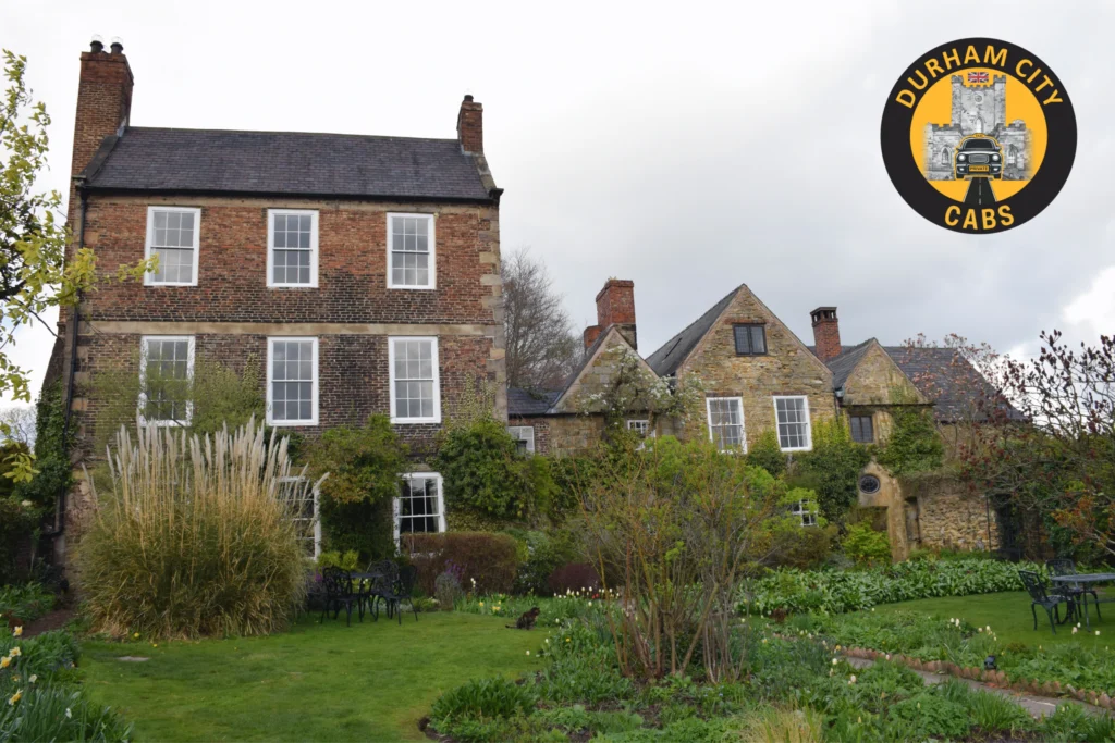 A view of the historic Crook Hall in Durham, showing its multiple architectural styles from across its lush, green secret garden.