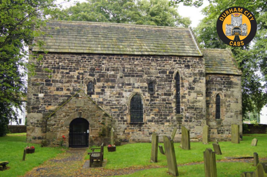 Exterior view of the ancient Escomb Saxon Church, a 1300-year-old stone building in County Durham, surrounded by a small graveyard.